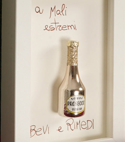 Cornice in legno "a Mali estremi Bevi e Rimedi" con una "Bottiglia di Prosecco Natalizia" in metallo